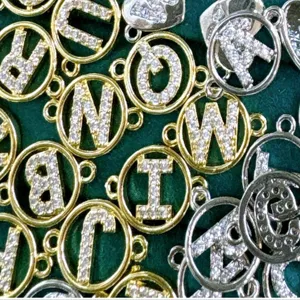 Primer plano y detalle de dijes con letras de pedrería y colgantes de circonita para joyería.