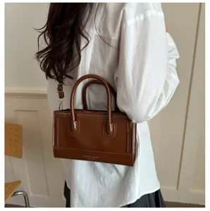 Detail view of brown patent leather retro handbag, showing texture and handle craftsmanship.