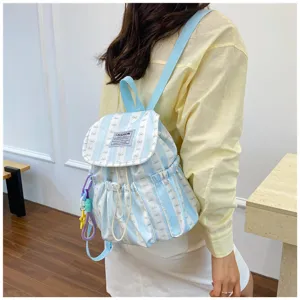 Close-up detail of light blue striped backpack with bow pattern and cute side hanging charms.