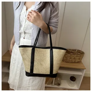 Close-up view of the summer straw tote bag featuring black leather handles and trim detail.