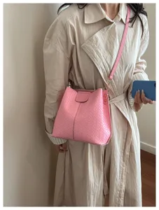 Pink woven bucket bag for women, stylish leather crossbody shoulder bag for daily commute.
