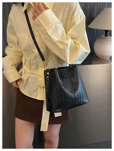 Black woven leather bucket bag with shoulder strap, classic chic design for daily commute.