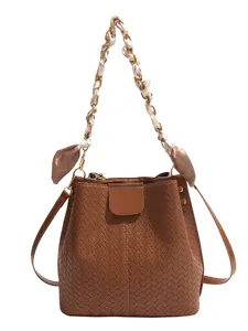 Trendy brown woven bucket bag with chain and scarf handle, stylish retro shoulder bag.