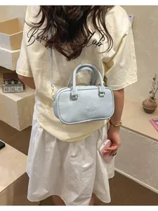 Detailed view of a light blue crossbody shoulder bag, featuring dual top handles and zipper.