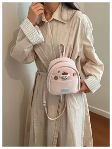 Détail de mini sac à dos rose avec adorable pendentif chien en peluche et poche avant.