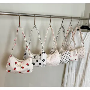 Display of various printed casual shoulder bags hanging on a metal rack in detail view.
