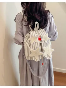 Detailed view of striped canvas backpack featuring fluffy star decorations and comfortable straps.