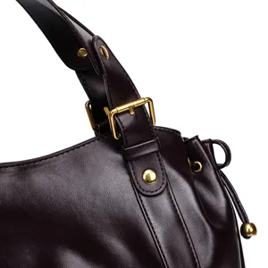 Close up of leather handbag strap detail with golden metal buckle and soft brown texture.