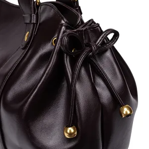Detailed view of women soft leather drawstring shoulder bag with elegant gold metal tips.