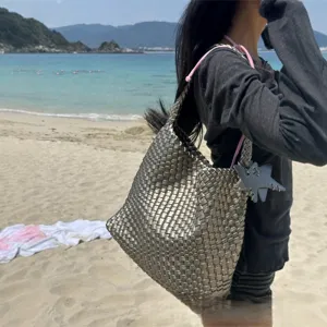 Lightweight metallic woven shoulder bag with pink drawstring and star charm for women beach use.