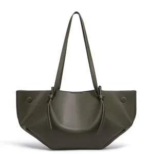 Nahaufnahme einer dunkelgrünen PU-Ledertasche mit einzigartigem Faltdesign und langen Trägern.