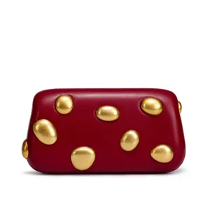 Detailed view of burgundy women shoulder bag featuring unique gold pebble studs and smooth leather.