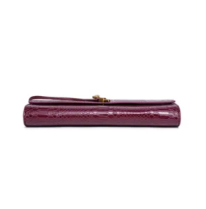 Close-up of burgundy snakeskin texture evening clutch bag with metallic lock detail.