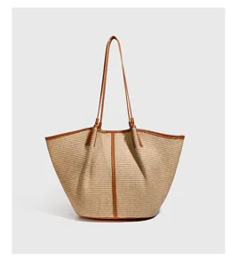 Detail van de geweven raffia tote tas met bruine lederen afwerking en stijlvol strandontwerp.