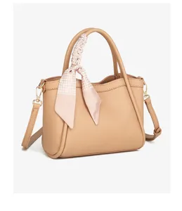 Vista detallada del elegante bolso cubo de piel caqui adornado con un pañuelo de seda rosa.