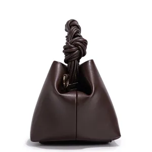 Dark brown leather handbag detail showing the exquisite knotted handle and smooth texture.