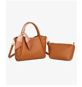 Bolso tipo cubo de cuero marrón con pañuelo y cartera a juego, elegante diseño cruzado.