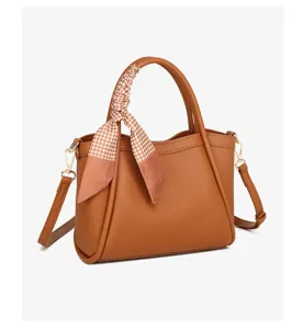 Detalle de bolso de cuero marrón, pañuelo pata de gallo, elegante bolso de hombro.