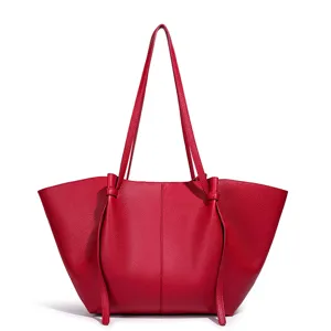 Rode lederen tote tas detail met fijne textuur, vleugel ontwerp en lange schouderband.