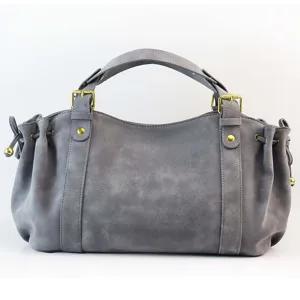 Gedetailleerd uitzicht op de grijze retro suède trekkoord baguette tas met gouden hardware.
