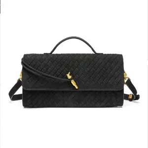 Black woven leather baguette shoulder bag featuring artisanal texture and gold knot.
