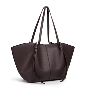 Donkerbruine lederen tote bag detail, met gestructureerde afwerking en lange banden.