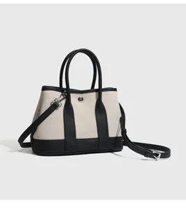 Dettaglio della piccola borsa in tela a contrasto, finiture in pelle e tracolla.