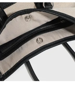 Dettaglio interno borsa tote in tela e pelle con fodera a spina di pesce resistente e hardware.