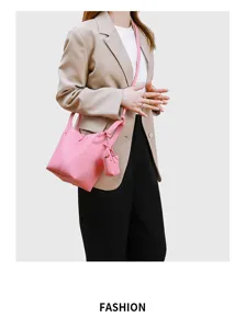 Detailansicht der eleganten minimalistischen rosa Eimer Tasche mit Henkel und Mini-Beutel Anhänger.