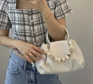 Nahaufnahme der weißen plissierten Cloud Handtasche mit marmoriertem Perlenhenkel.