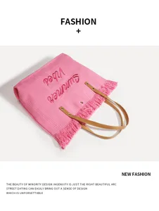 Detalle de bolso de playa de punto rosa con ribete de flecos y texto bordado de verano.