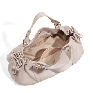 Detailed view of the spacious interior compartments and golden zippers of the beige bag.