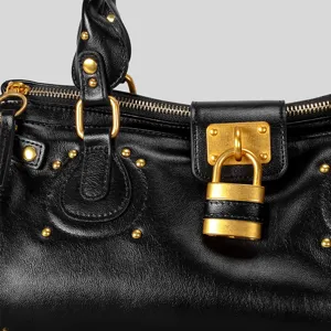 Primo piano dettaglio di borsa Boston vintage in pelle nera con lucchetto e dettagli oro.