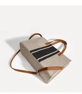 Canvas Shopper Detailansicht mit schwarzen Streifen, braunen Ledergriffen und verstellbarem Gurt.