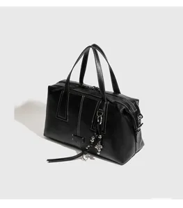 Detalle de bolso boston de cuero negro, bolso de mano bowling vintage con cruz.