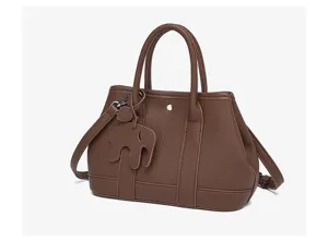 Brown leather tote bag with elegant double handles and cute elephant charm for daily use.