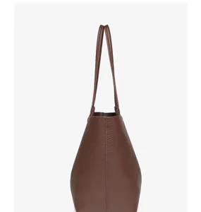 Bruine PU leer tote tas zijaanzicht detail met fijne textuur en slanke dubbele handvatten.