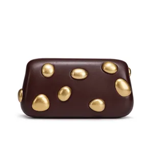 Detail of unique brown clutch bag with golden pebble studs, chic underarm handbag style.