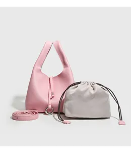 Vista detallada del bolso tipo cubo de piel rosa con bolsillo interior y correa.