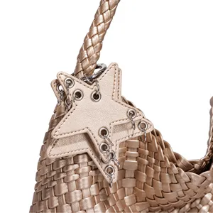 Gold woven handbag detail, metallic star pendant with grommets and chains for stylish look.