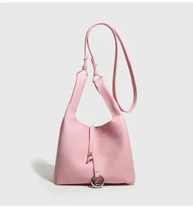 Vista detallada del bolso tipo cubo de cuero rosa con cierre de anillo elegante y correa.
