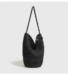 Vista detallada del bolso hobo negro tejido a mano con una textura de punto única.
