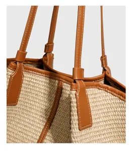 Raffia geweven tote tas detail met premium stroo textura, bruine lederen handvat en stiksels.