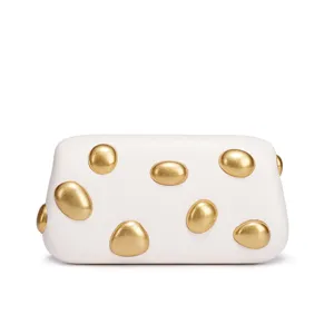 Detail view of a white leather clutch bag with unique gold pebble metal studs and stylish ornaments.