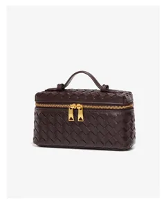 Detaillierte Nahaufnahme der dunkelbraunen geflochtenen Kosmetiktasche mit Griff.