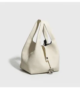 Vista detallada del elegante bolso cubo de cuero beige con herrajes de metal fino.