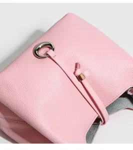 Detalle de bolso cubo de cuero rosa con material texturizado suave y cierre de anilla de metal.