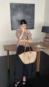 Detailopname van een geweven raffia tote bag met lederen handvatten in kamerstijl.