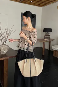 Gedetailleerd overzicht van de grote raffia strooien tote tas met lederen handvatten.