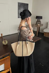 Detailweergave van de raffia strooien tote tas met geweven textuur en stijlvolle lederen schouderband.
